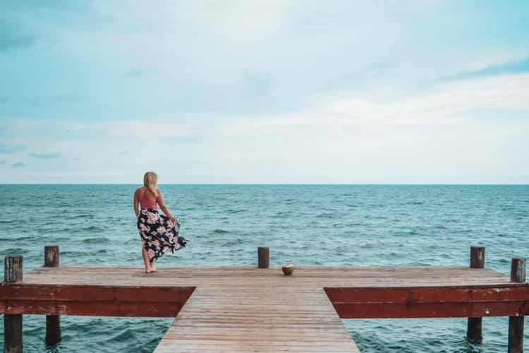 Woman standing at the edge of a dock holding her skirt in Belize