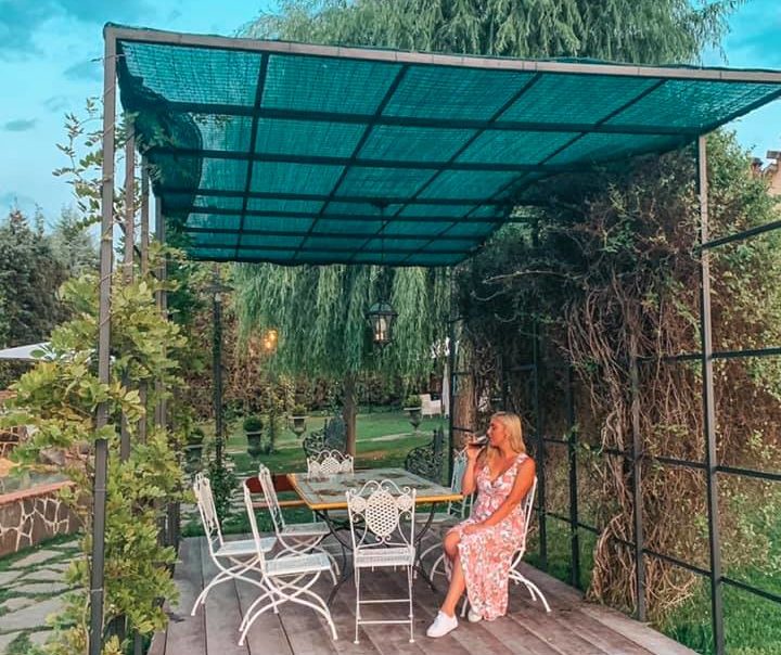 American woman sipping a glass of wine in Tuscany, surprised to find out she didn't get a headache.