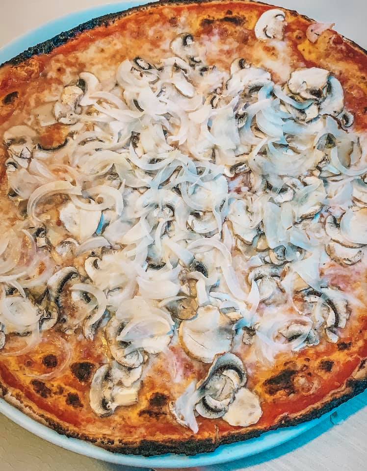 an enormous Roman pizza covered in mushrooms and onions