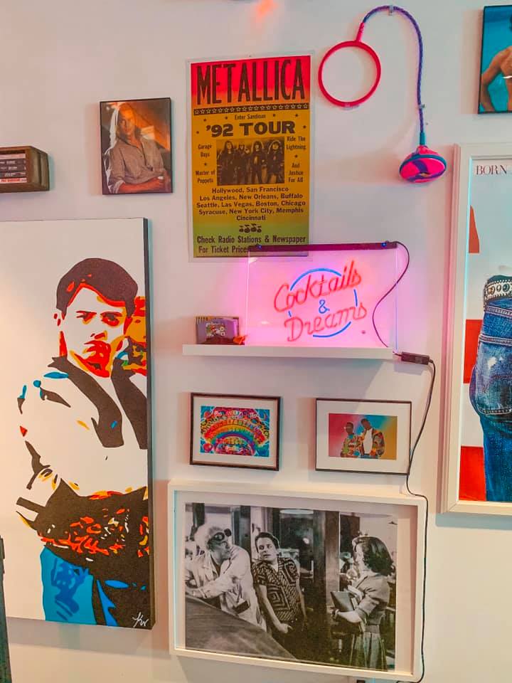 White wall covered with Ferris Buehler and other throwback references, as well as a neon sign that reads Cocktails & Dreams