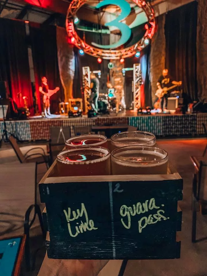 Cider flight held up in front of the stage located in 3 Daughters