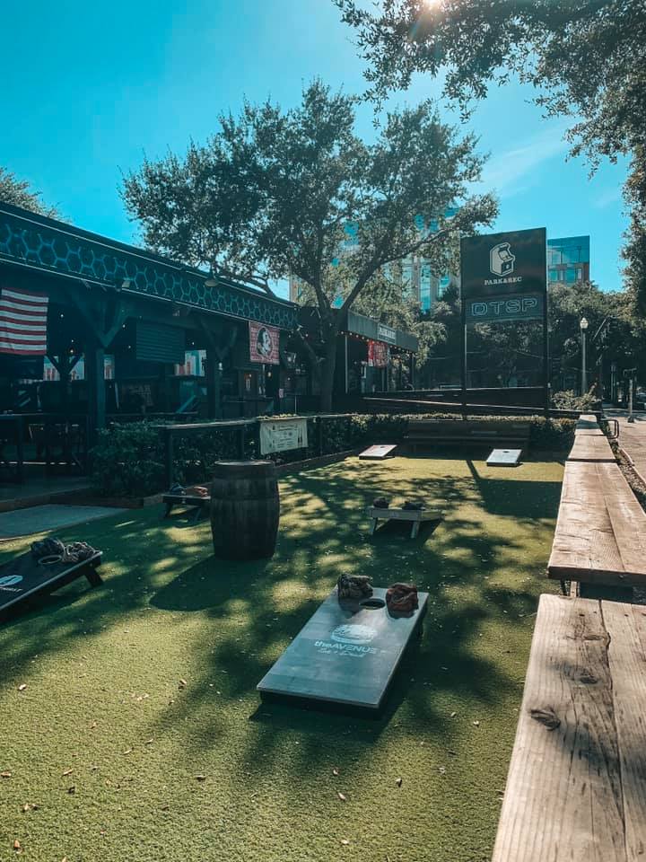 Outside Park and Rec setup with numerous cornhole games on the lawn