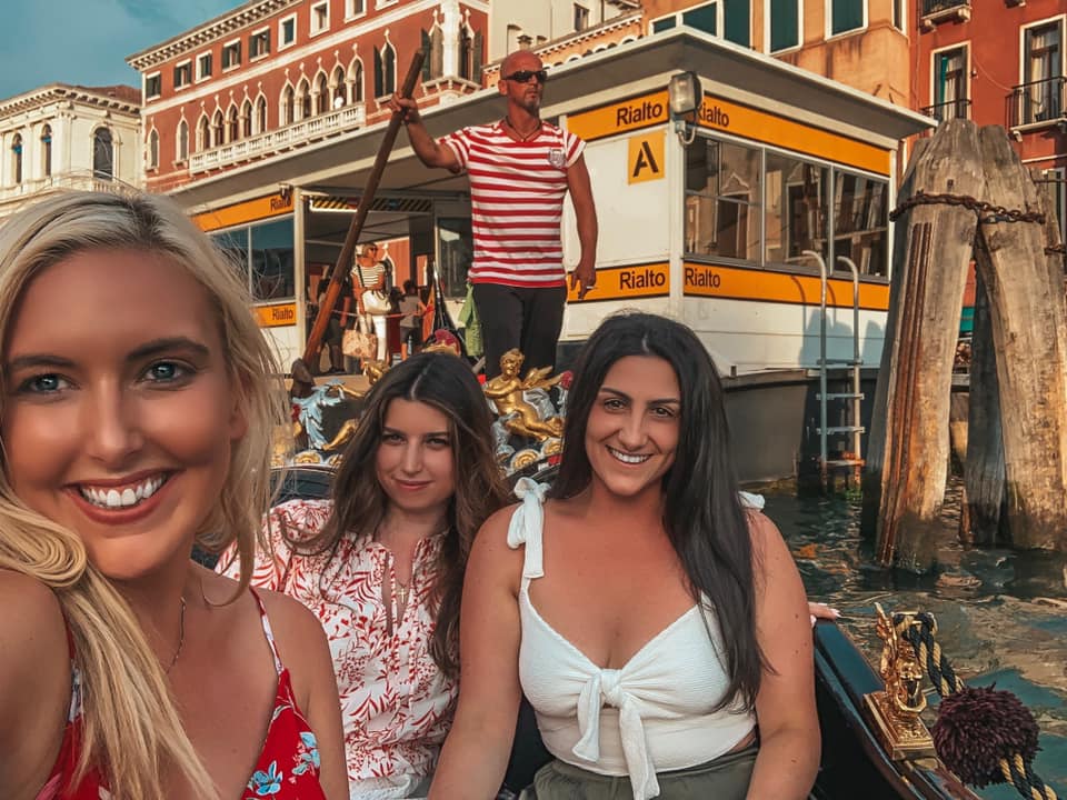 Three girls taking a selfie in a gondola in Venice, Italy. Meeting friends while traveling alone