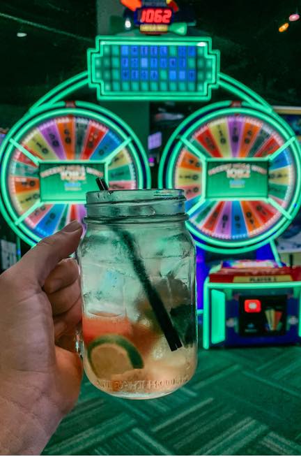 holding up a cocktail in front of Wheel of Fortune game at Gametime in Ybor Tampa