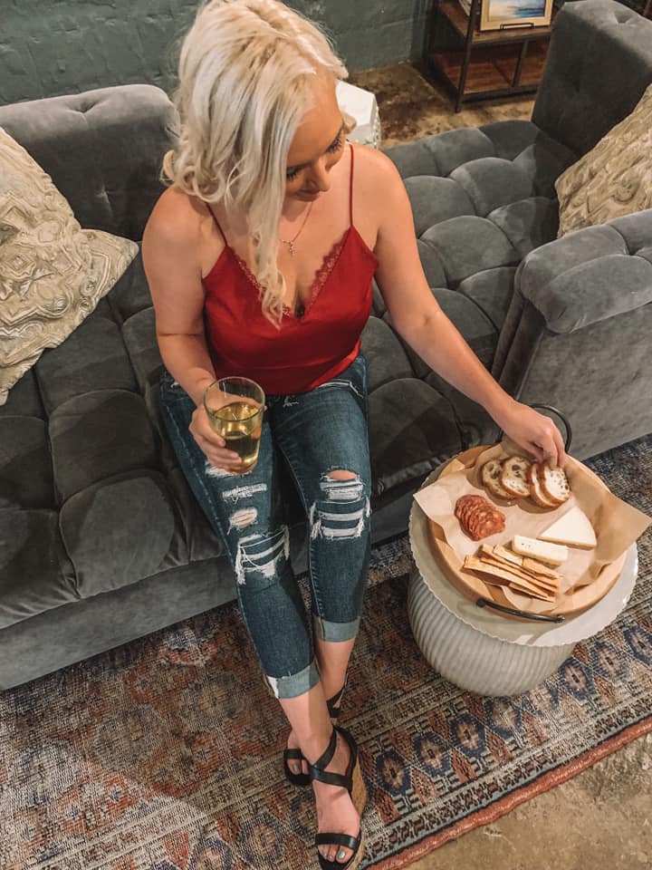 above shot of woman in red top grabbing a piece of pita off of a charcuterie board