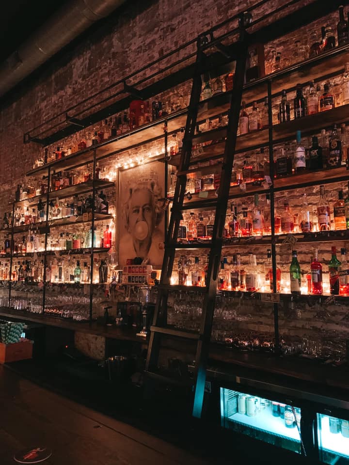 Unknown Caller bar area with liquor bottles and bar ladder