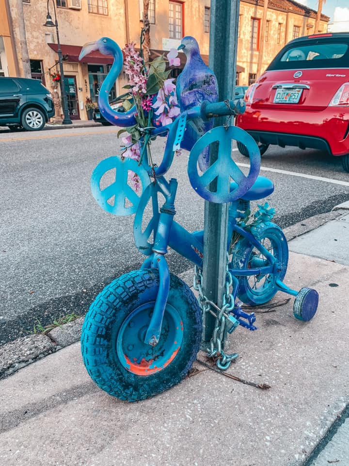 Purple painted tricycle locked up to a street sign