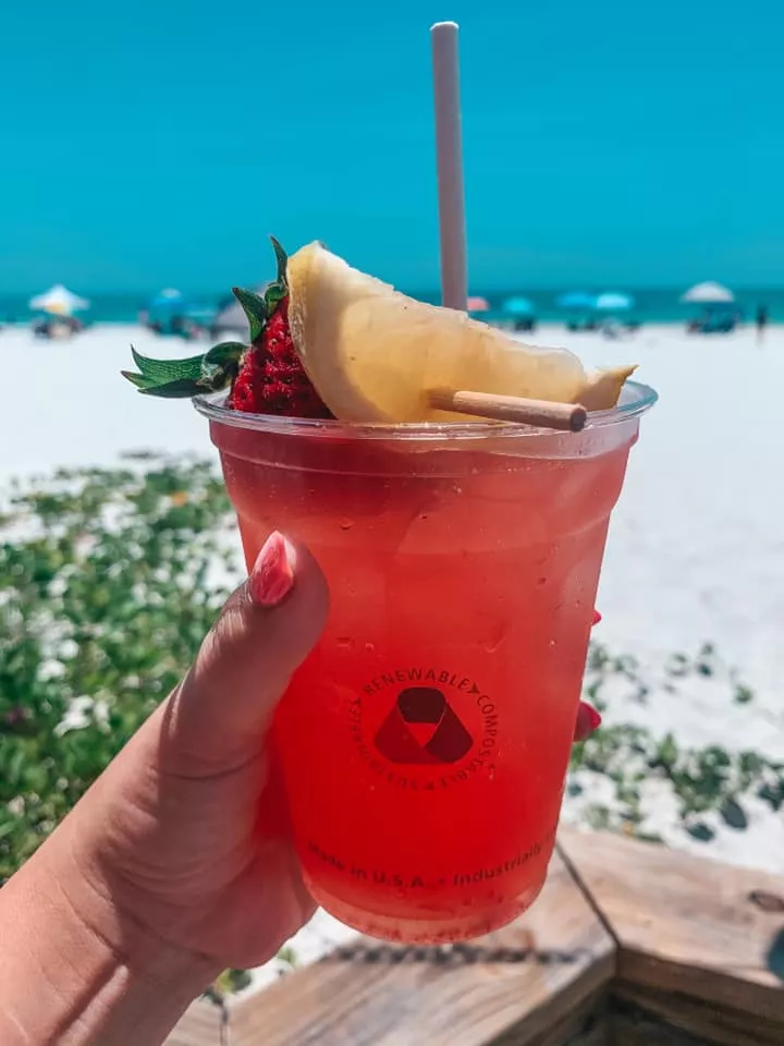 Fun fruity drink from Sandbar being held up in front of the Anna Maria Island beach