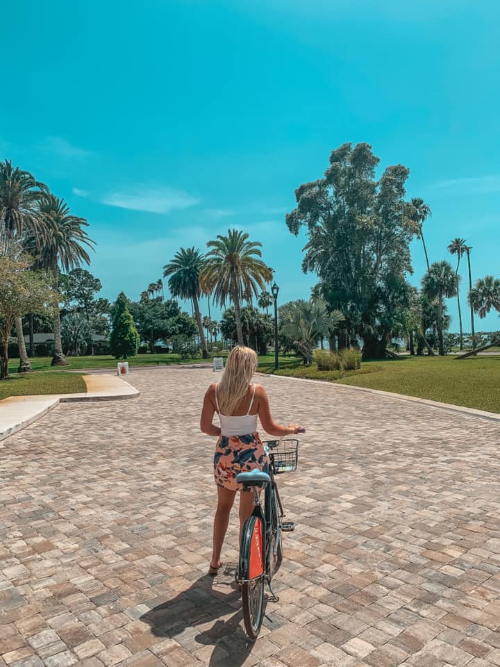 Woman standing next to and holding bicycle while looking out at Dunedin, Florida