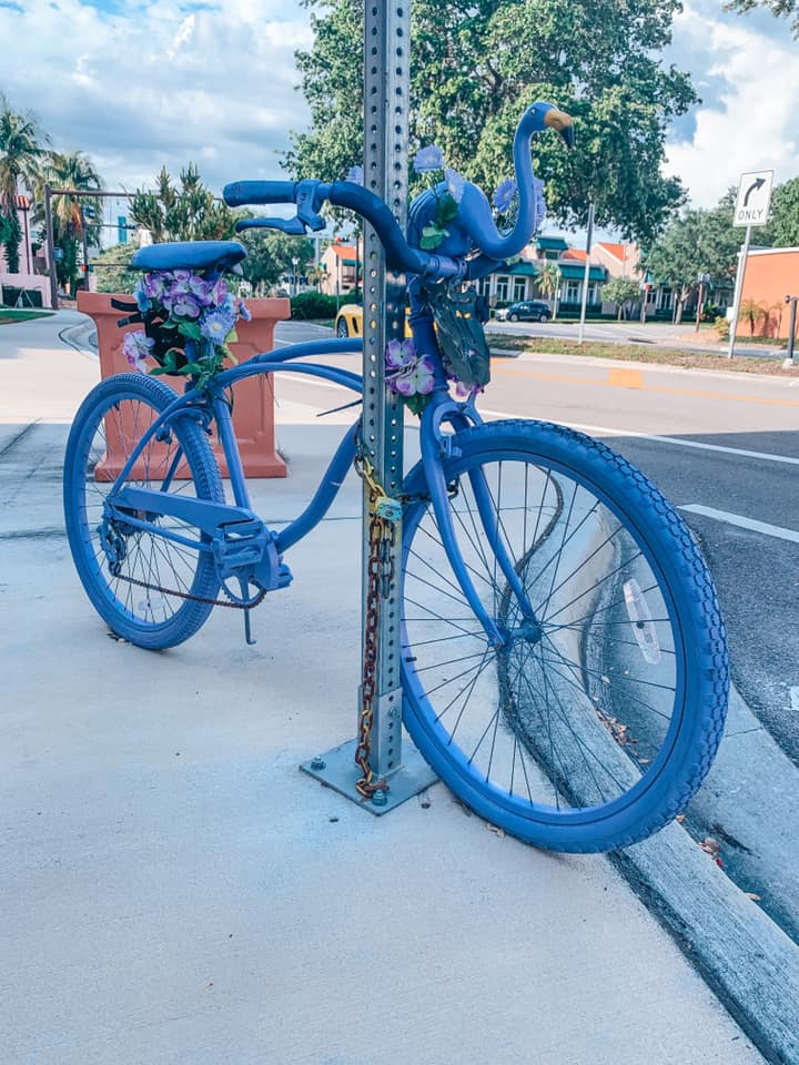 Purple painted bicycle locked up to a street sign. One of the most unique things to do in Sarasota, Florida