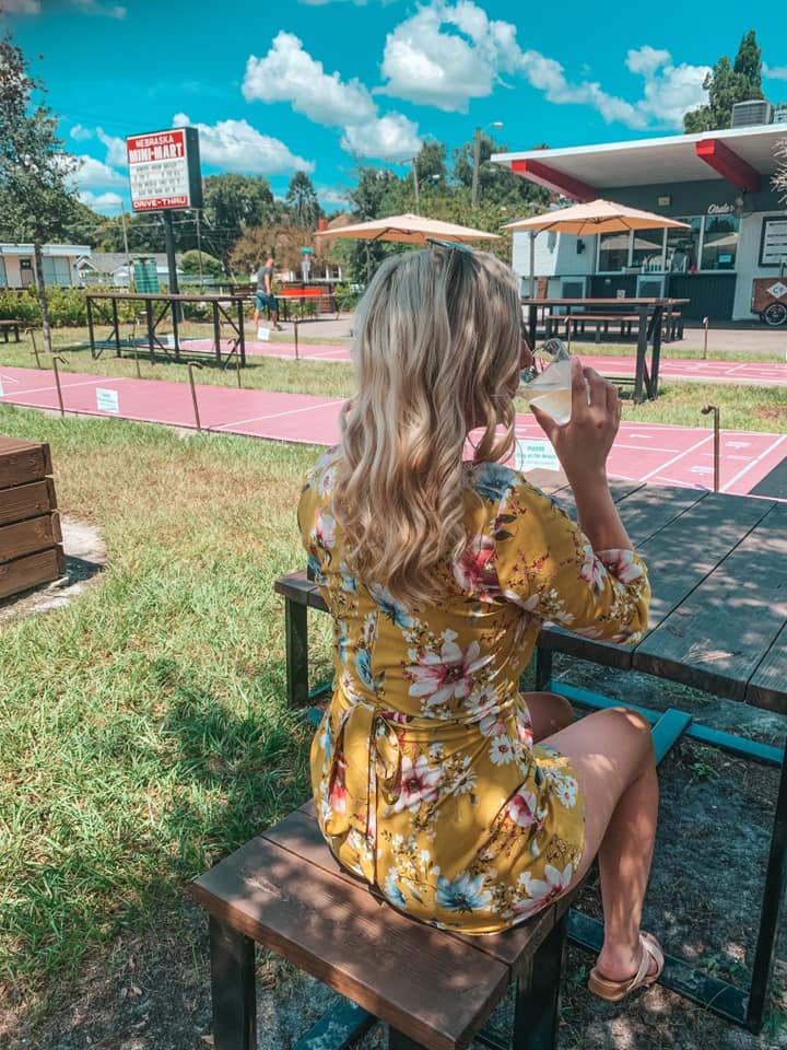 Destiny in a yellow romper enjoying a cocktail at Nebraska Mini Mart