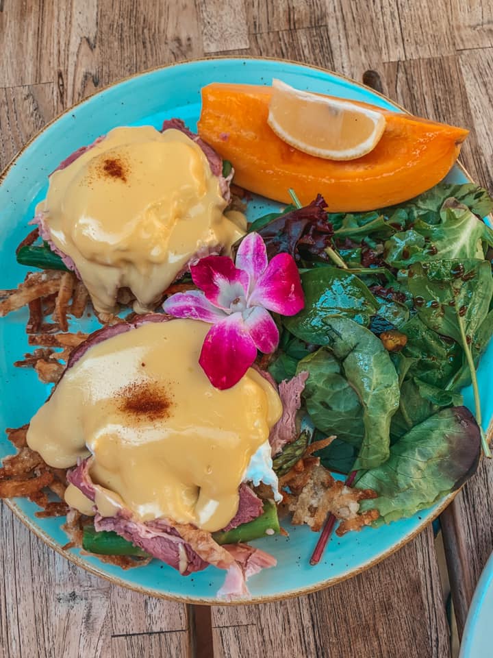 Eggs benedict, some greens, and a mango beautifully plated from Island Vintage Coffee