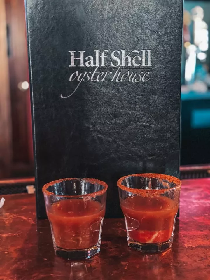 Two oyster shooters with an Old Bay rim in front of Half Shell Oyster House menu