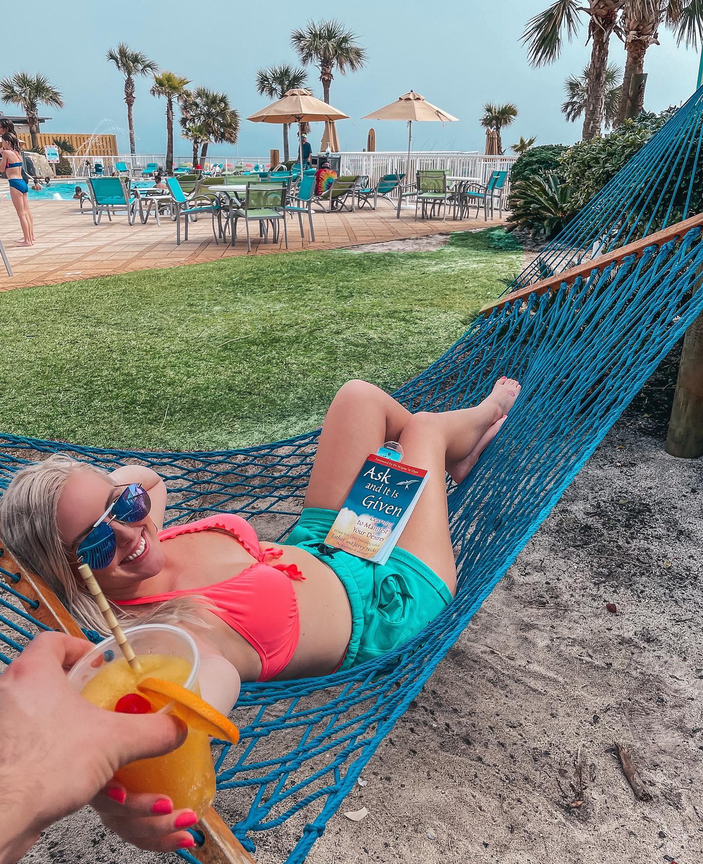 Enjoying the hammock at Holiday Inn Express Orange Beach while being handed a fun, orange drink. Most enjoyable things to do in Orange Beach.