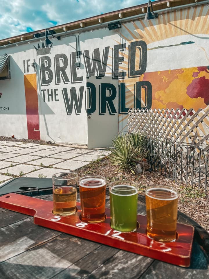 Beer flight on the patio in front of "If I brewed the world" mural