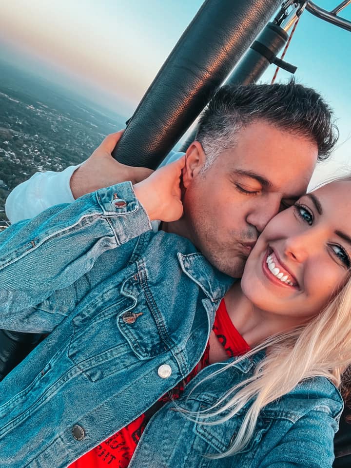 Man kissing a woman's cheek while on a hot air balloon ride for a romantic date in Tampa