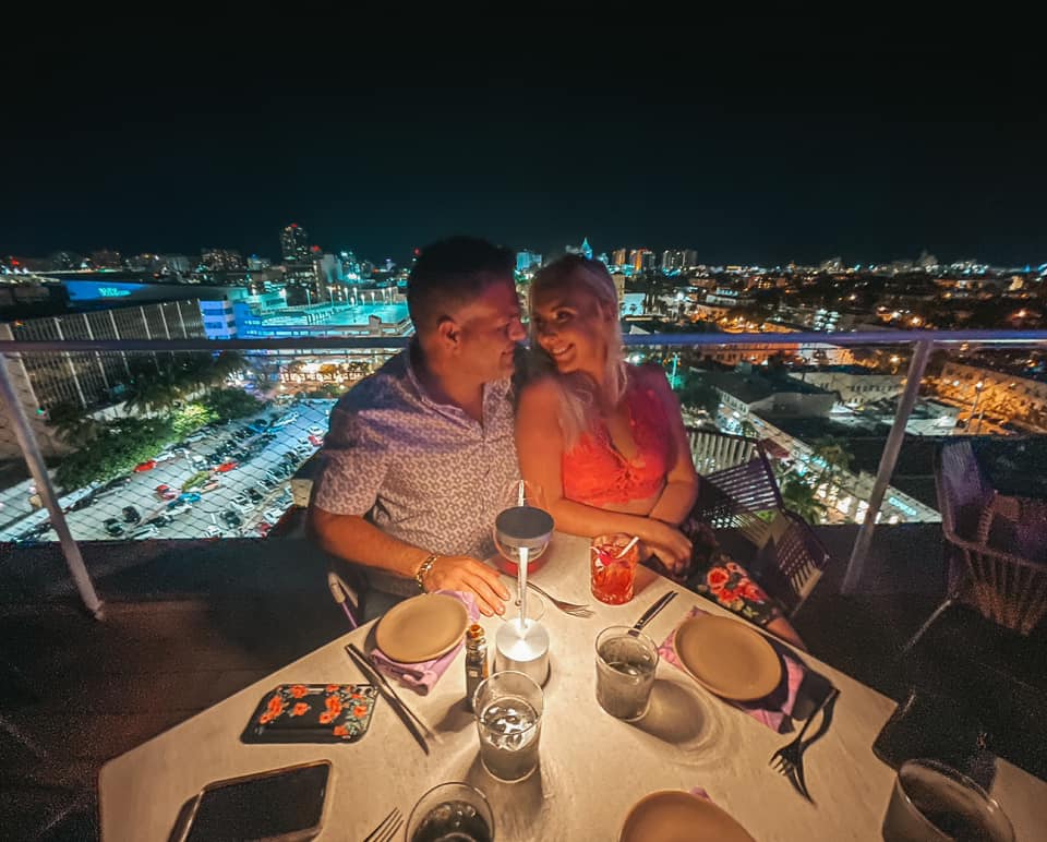 Couple enjoying cocktails and night views from Juvia rooftop in Miami