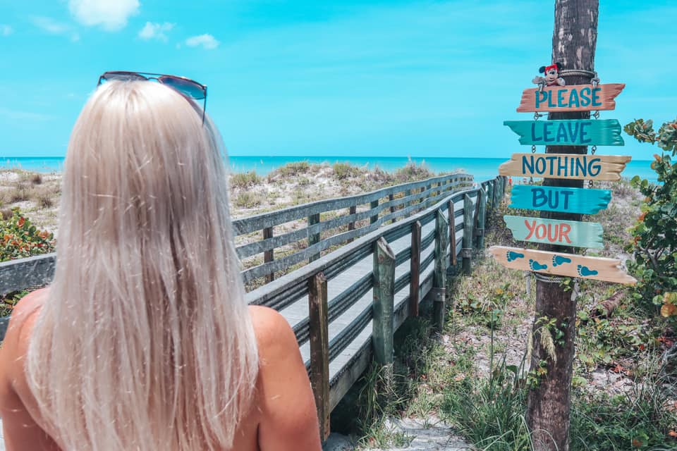 Blonde woman looking at "please leave nothing but your footprints" sign