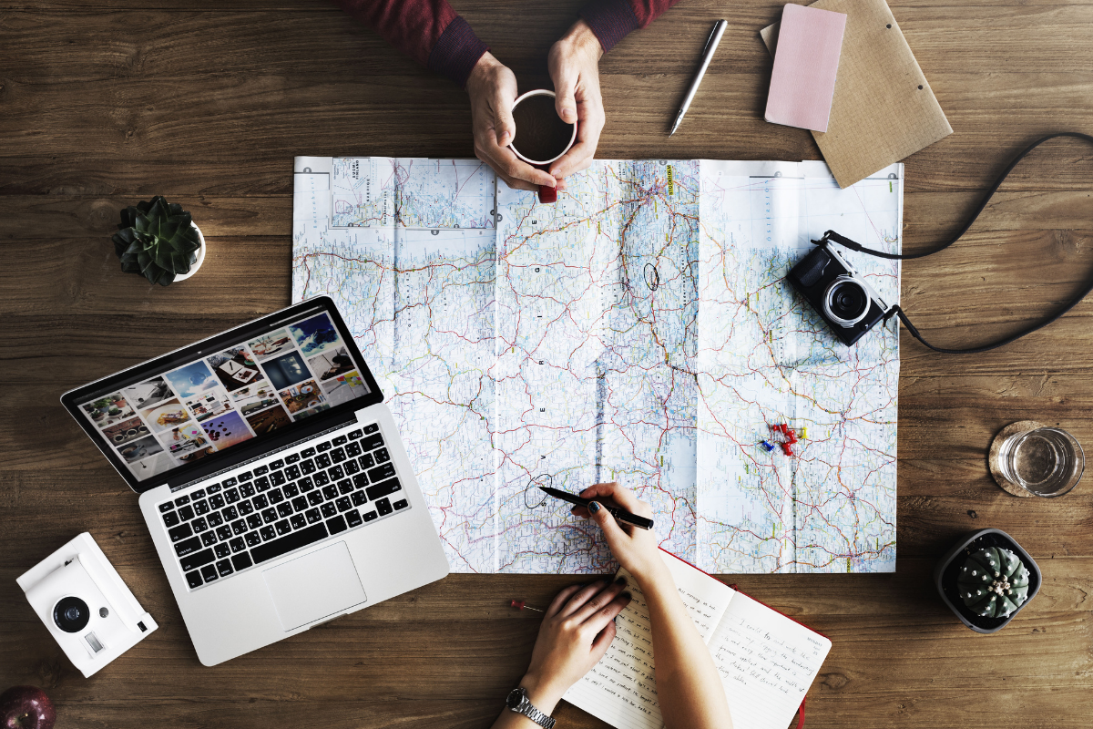 Map, camera, and laptop. One of the benefits of using a travel agent is they do the planning for you.