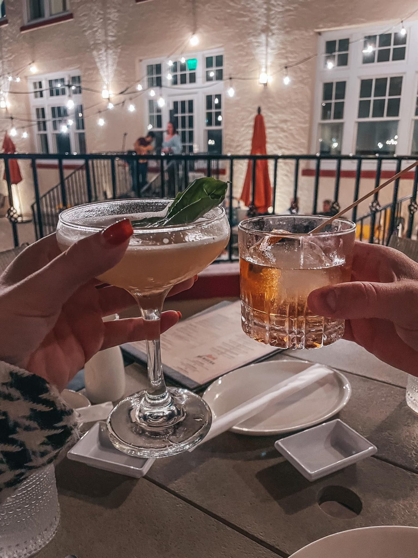 two hands cheersing drinks at HEW Chophouse restaurant in Dunedin for date night restaurants