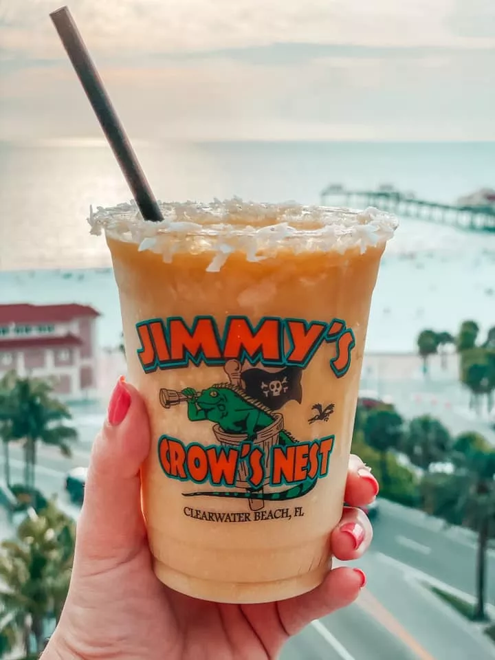 Mango pina colada being held up at Jimmy's Crows Nest rooftop bar in Clearwater Beach at sunset