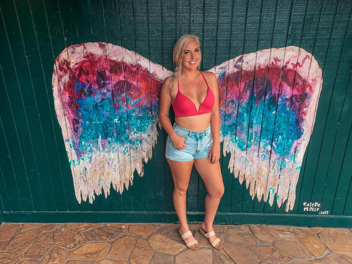 woman standing in front of wing mural in Haleiwa Town on the North Shore