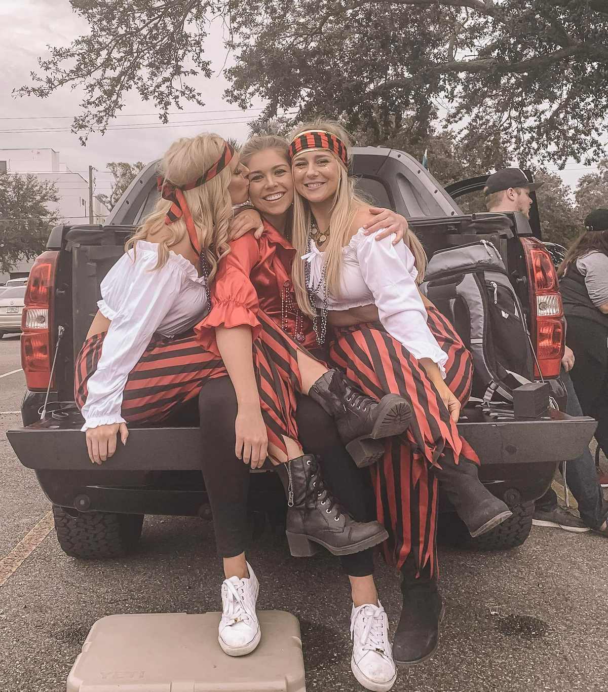 3 girls on a truck bed in pirate outfits celebrating Tampa's annual Gasparilla Festival