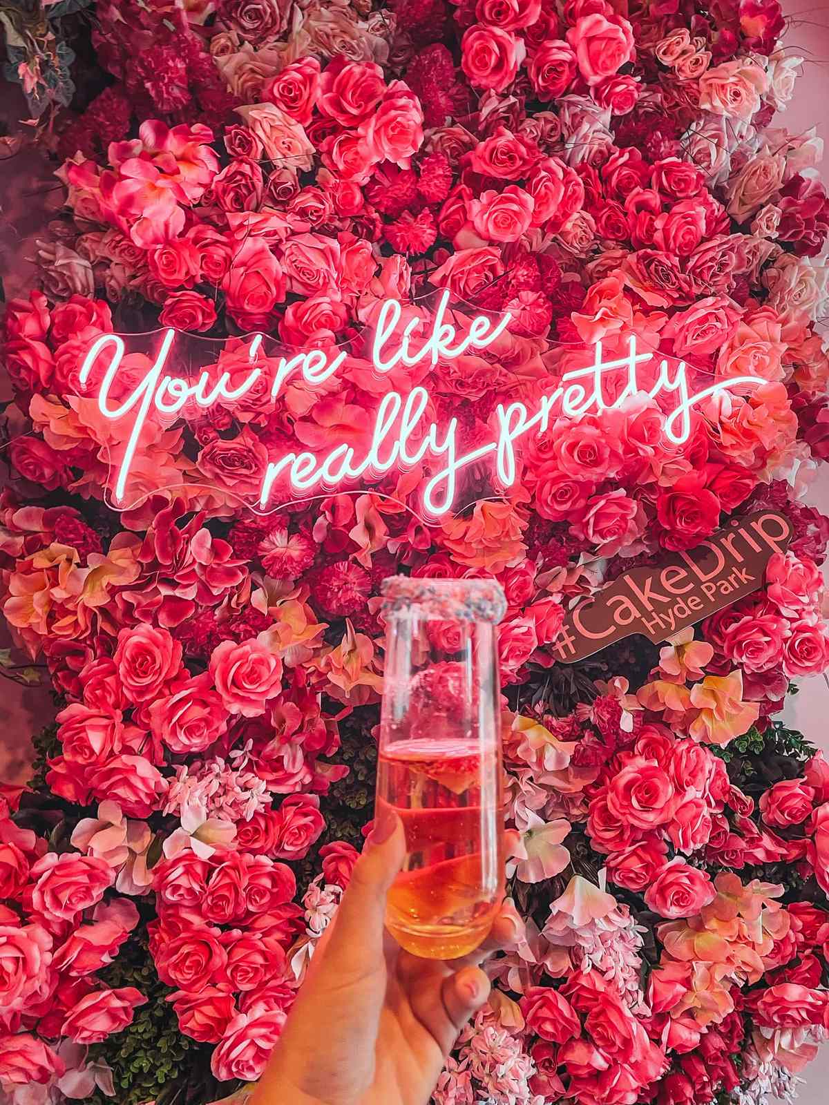 Champagne and neon sign that says "you're like really pretty" at Cake Drip in Hyde Park Tampa