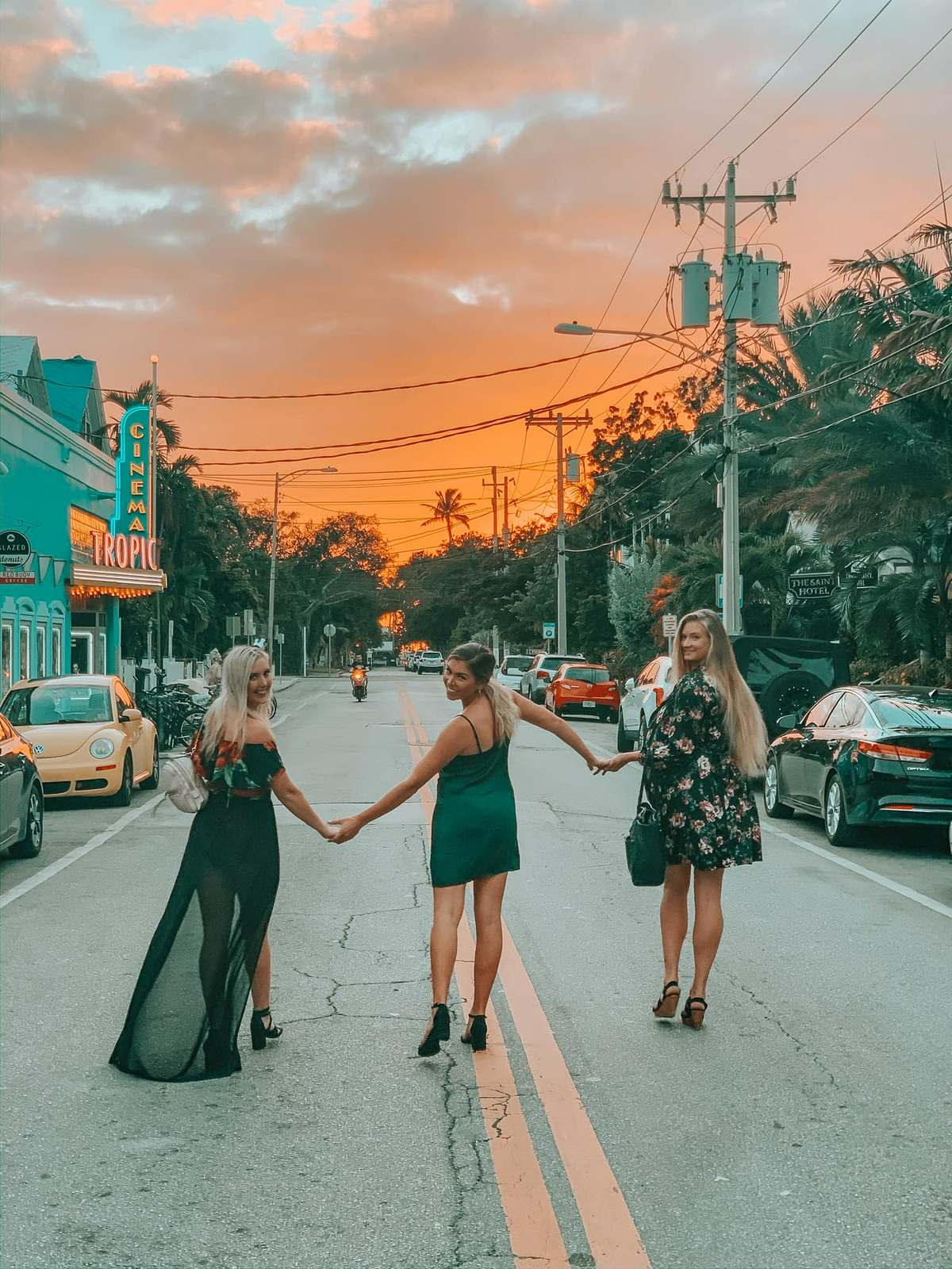 Three friends walking down the street holding hands in Key West at sunset