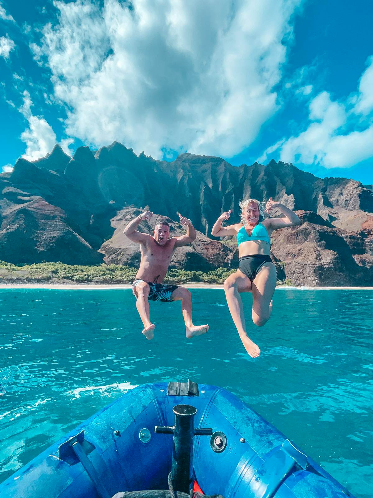 Couple jumping off of raft in front of Na Pali Coast for raft tour in Kauai