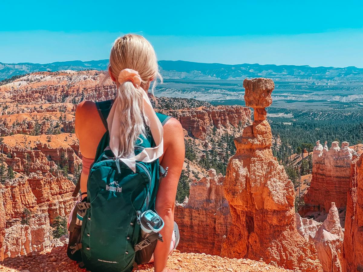 Woman sitting with hiking backpack on looking at Thors Hammer, one of the recognizable landmarks at Bryce Canyon National Park