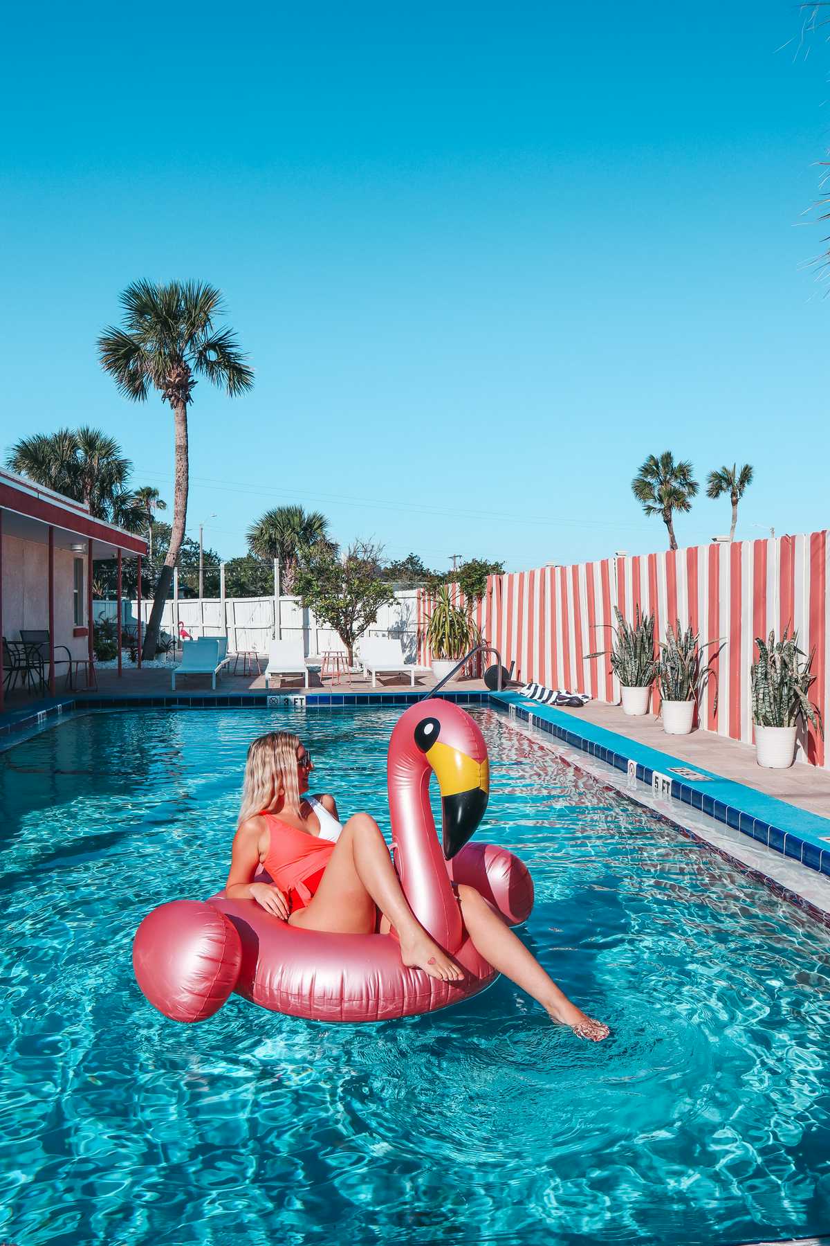 Woman sunbathing on a flamingo floaty at The Local motel pool
