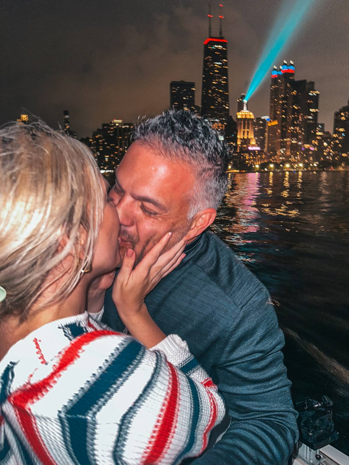 Couple kissing on a boat in front of Chicago at night