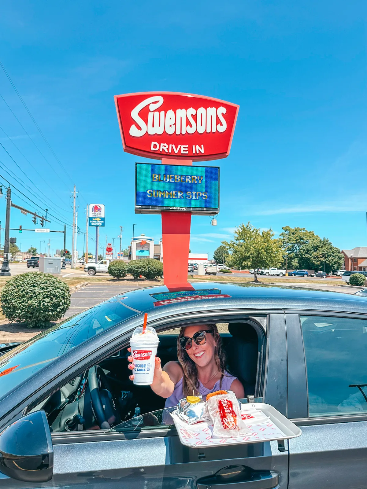 Woman holding milkshake and sitting in car at Swensons in Canton Ohio