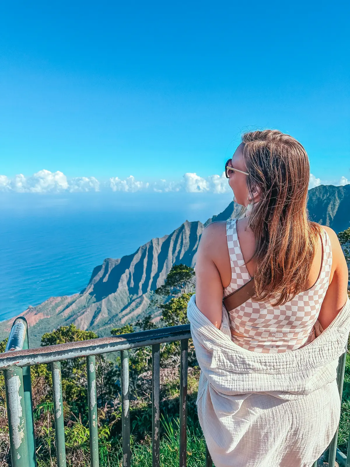 Woman looking out at views of Na Pali Coast at Kokeʻe State Park on Kauai