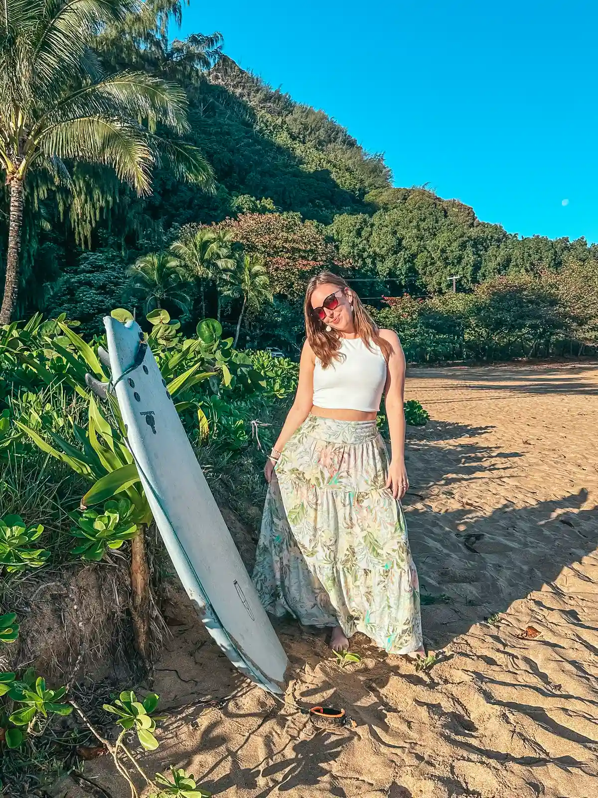 Woman posing with surfboard at Tunnels Beach on Kauai