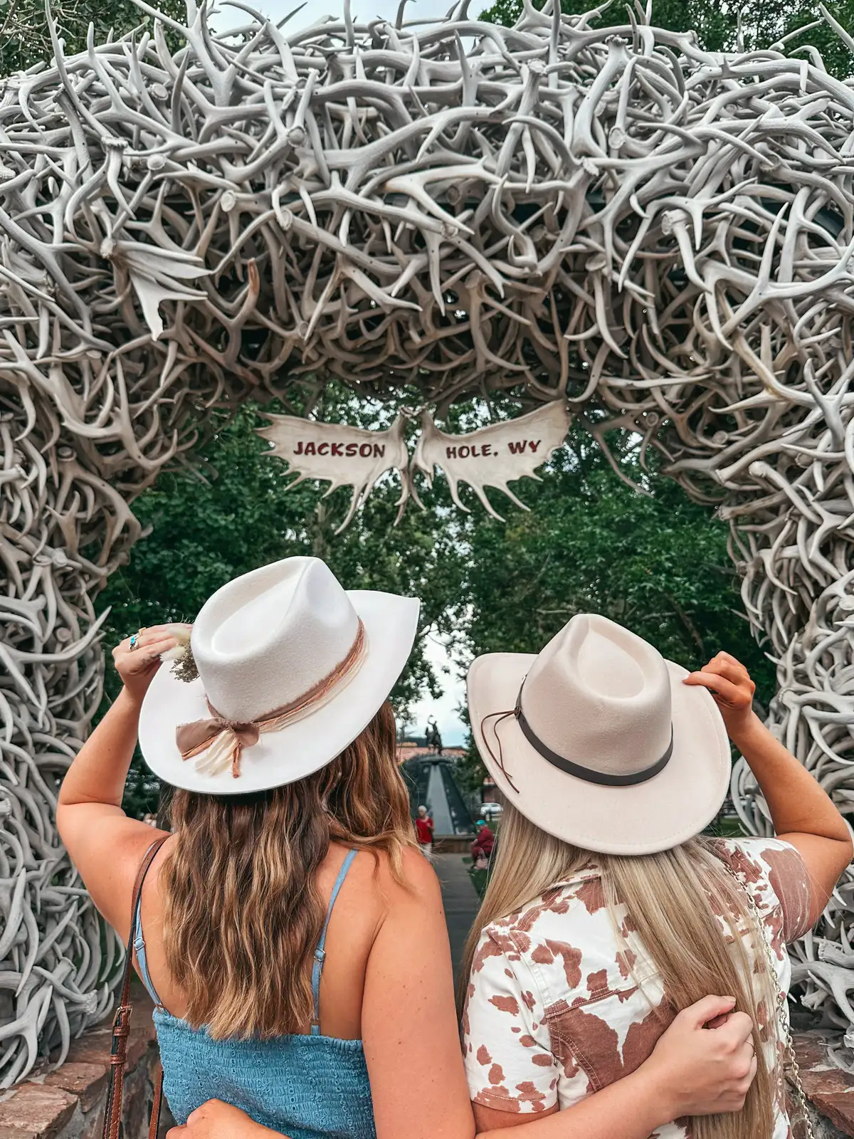 Friends Wearing Cowboy Hats Posing In Front Of The Antler Arches In Jackson Hole Wyoming