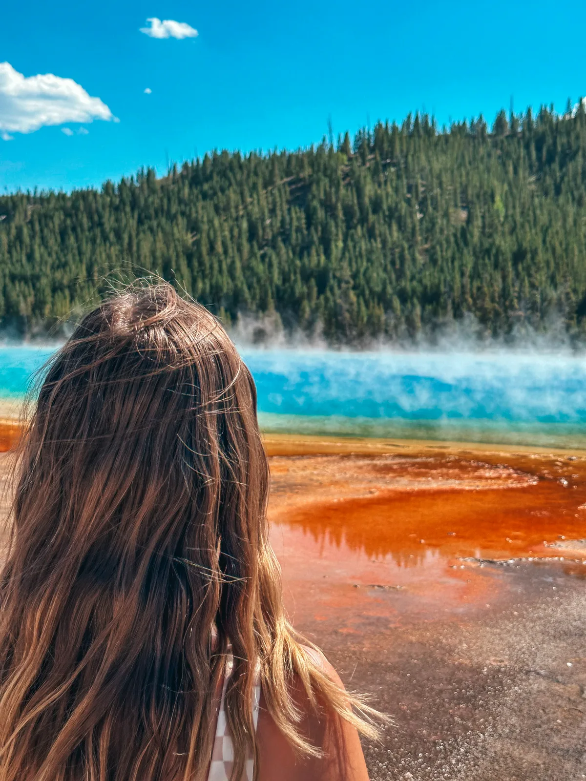 Woman Standing In Front Of Beautifully Rainbow Colored Grand Prismatic At Yellowstone National Park