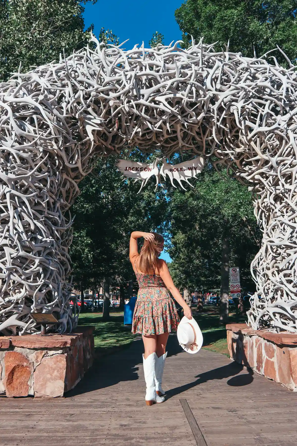 Women Posing By Holding Her Cowboy Hat At Her Side In Front Of Antler Arches In Jackson Hole Wyoming