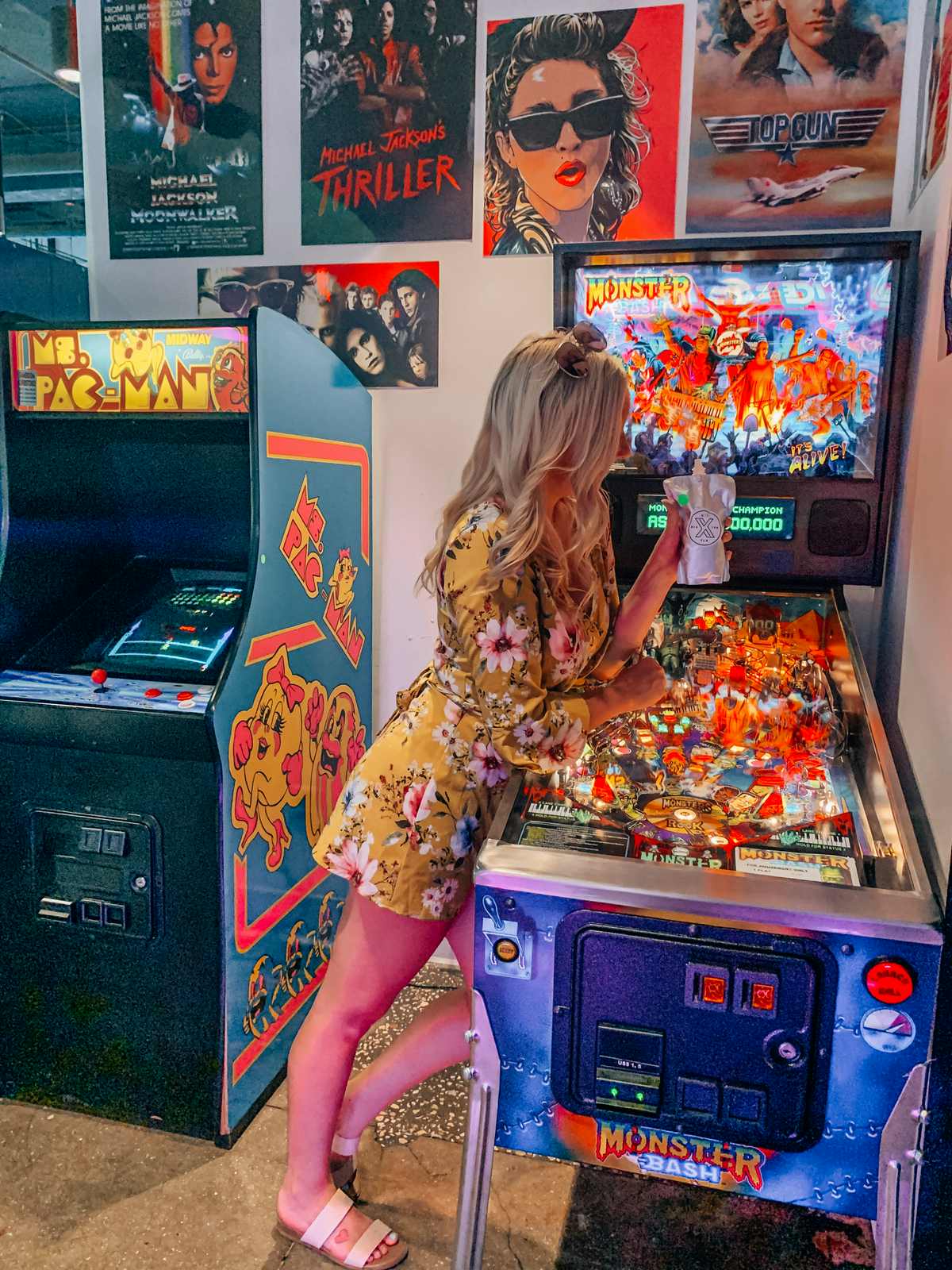 Woman drinking leaning against pinball machine at Gen X Tavern Arcade Bar Tampa