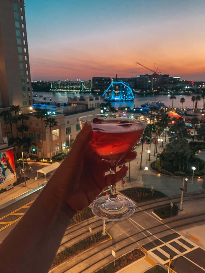 Holding Up Cocktail From Six Rooftop Bar In Tampa At Night